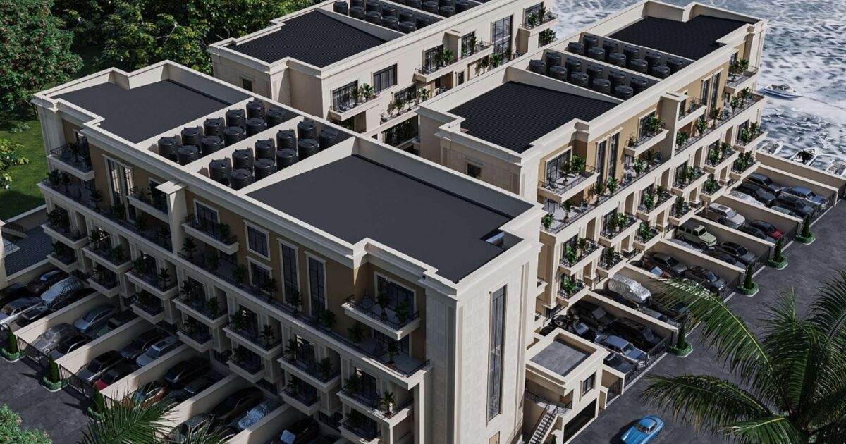 Aerial view of Tranquil Waterfront Homes at Patrick Harbour Estate — the building sits directly on the water with the Lagos harbour visible behind it